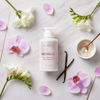 Monaco Body Glow Serum with white freesia, orchid petals and vanilla pods flat lay — luxury body serum
