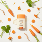 SKINFOOD Carrot Carotene Airy Sun Stick with fresh carrots and centella asiatica botanical ingredients flat lay
