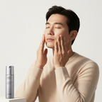 Korean man applying IOPE Men All Day Perfect All-in-One with fingertips, IOPE silver bottle in foreground, glowing skin
